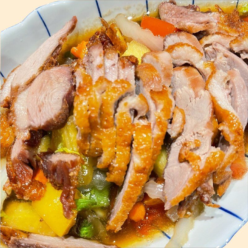Knusprig gebratene Ente (Pad Ped) in einer würzigen Sauce mit Ananas, Zwiebeln, Tomaten.